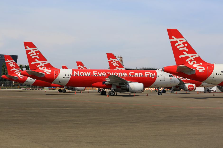 Multiple AirAsia airplanes parked on a tarmac at an airport, showcasing aviation travel.
