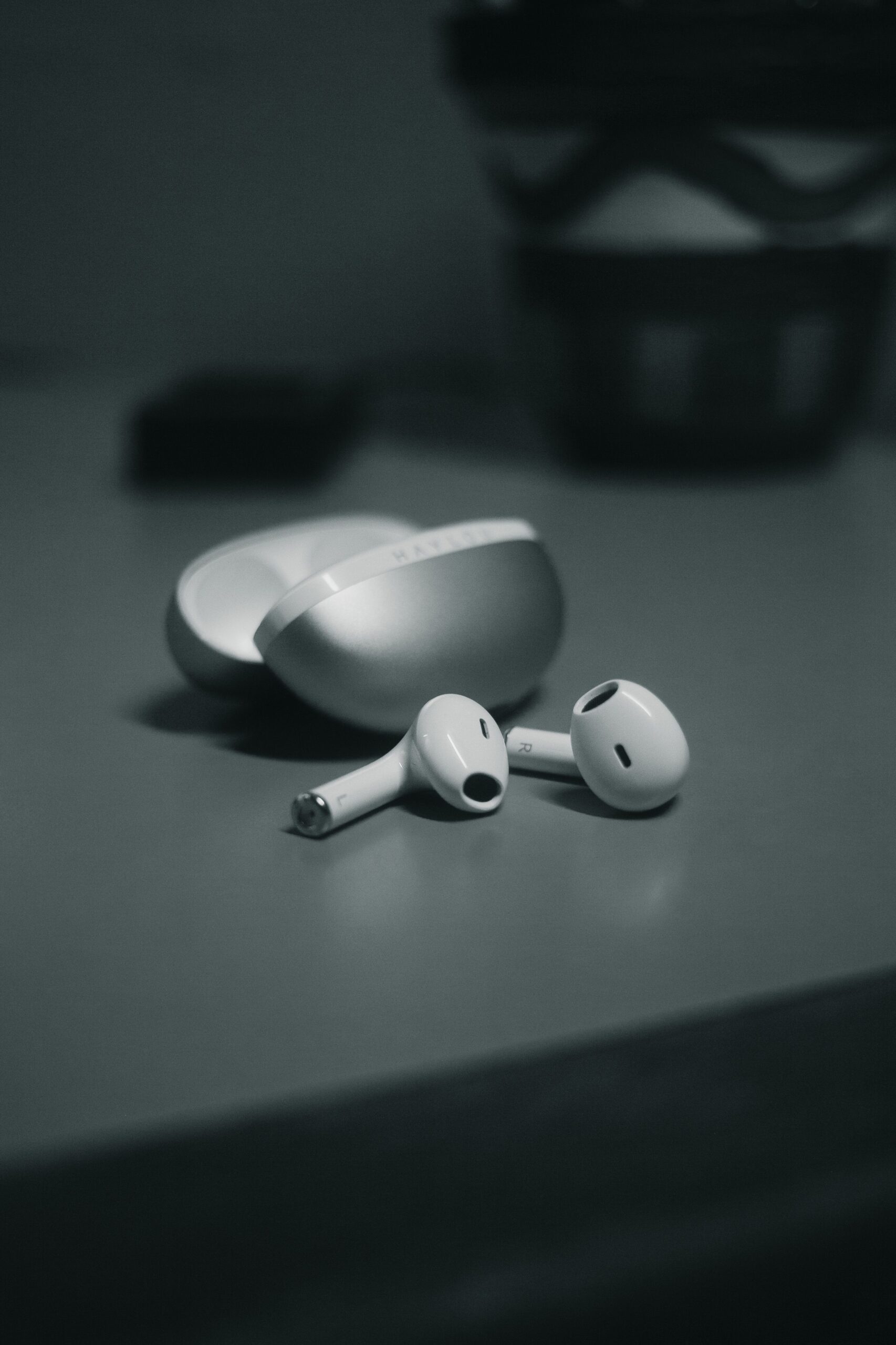 Minimalistic close-up of wireless earbuds with sleek design on a table in monochrome.