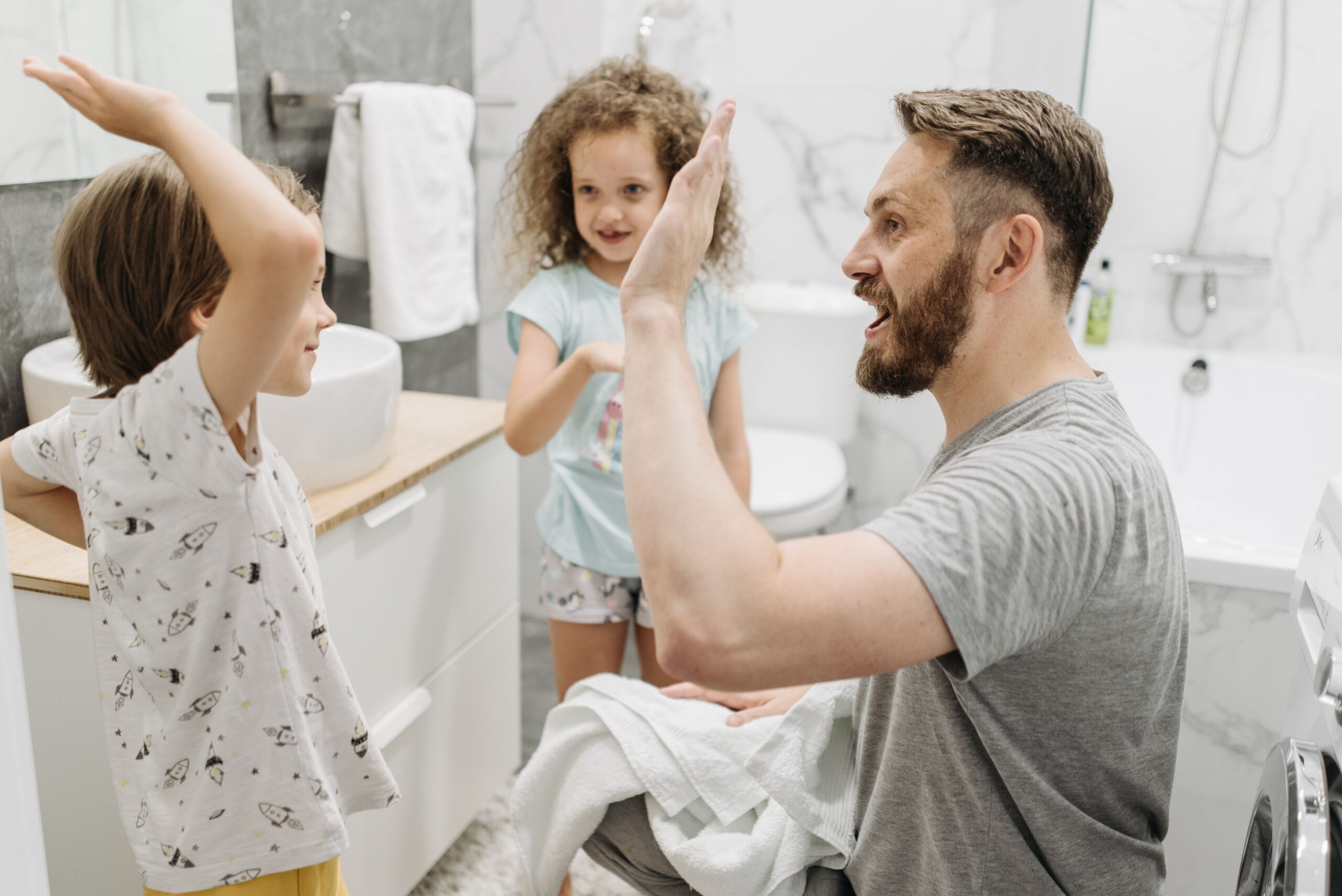 Father with son and daughter bonding during evening routine in bathroom.