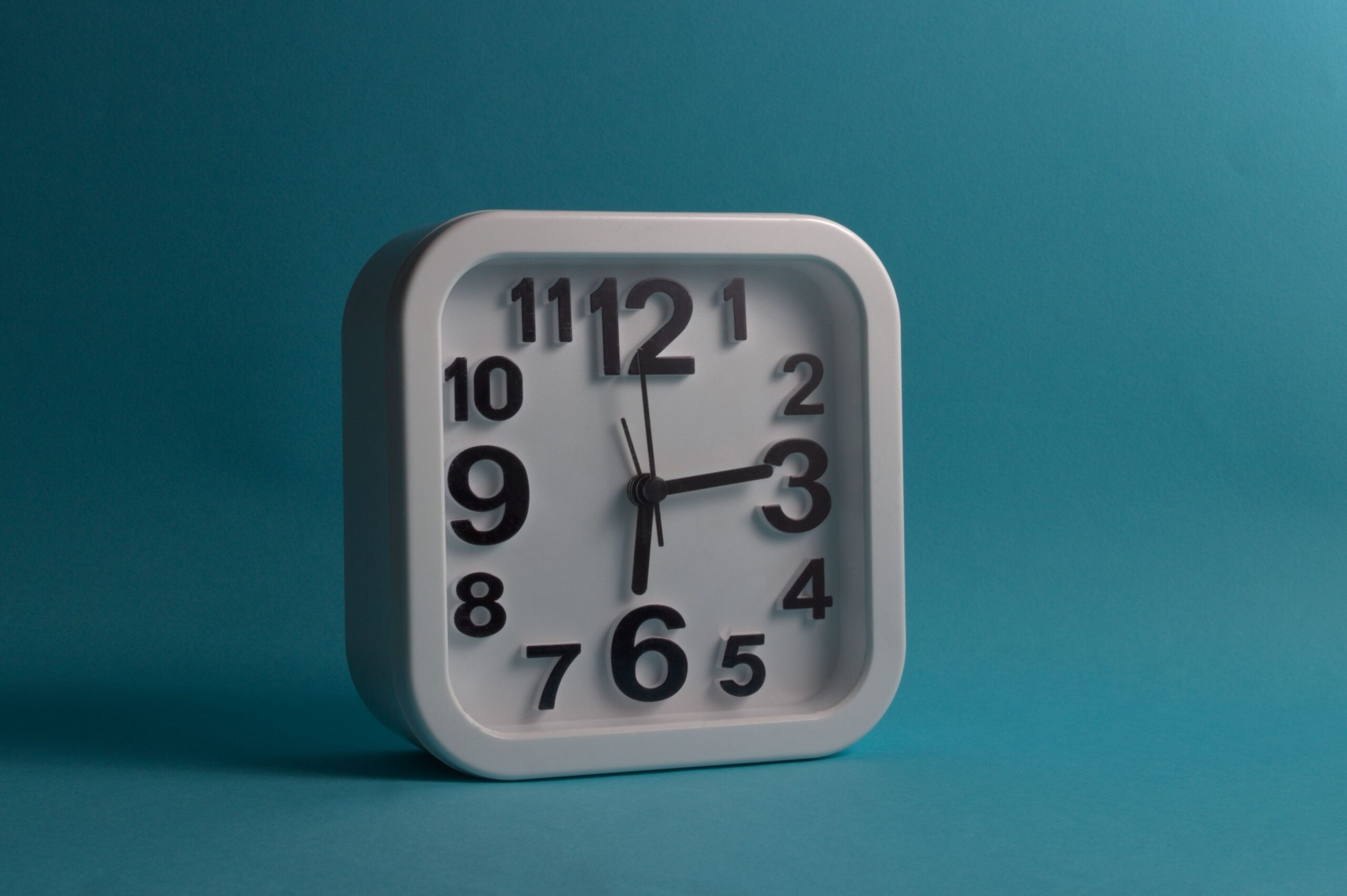 Square white wall clock displaying 10:10 against a blue backdrop, perfect for minimalistic and modern design themes.