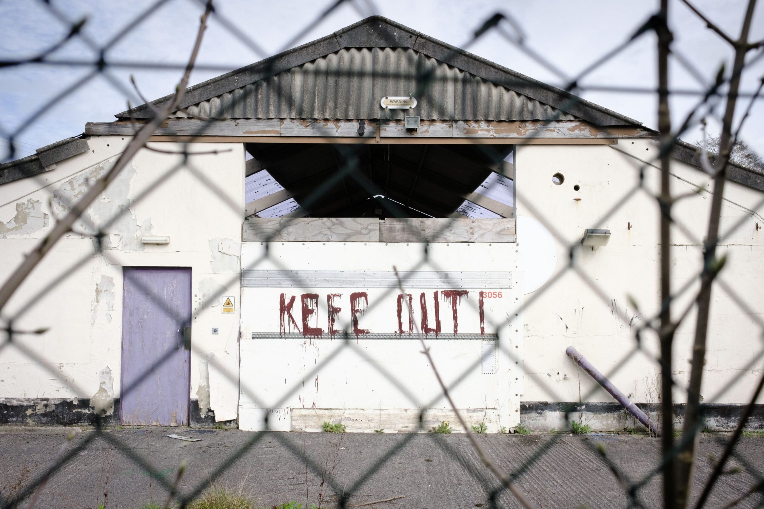 Dilapidated warehouse in Wotton-under-Edge, England, with a 'Keep Out' sign.
