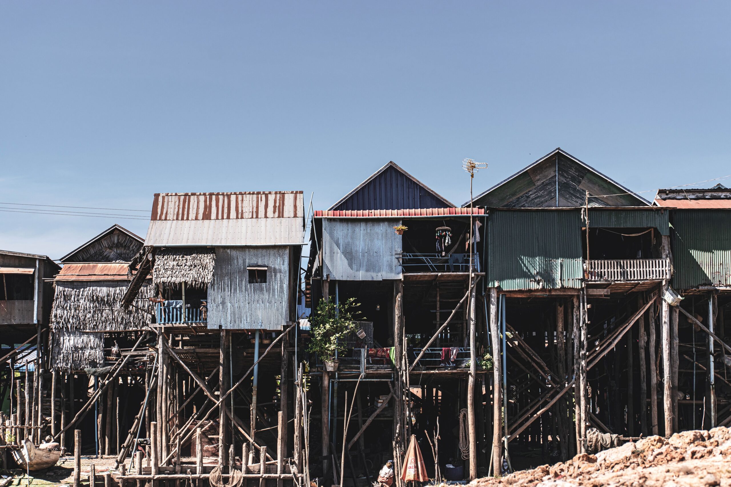 Stilt houses in Kampong Phluk, Siem Reap, showcasing traditional architecture against a clear sky.
