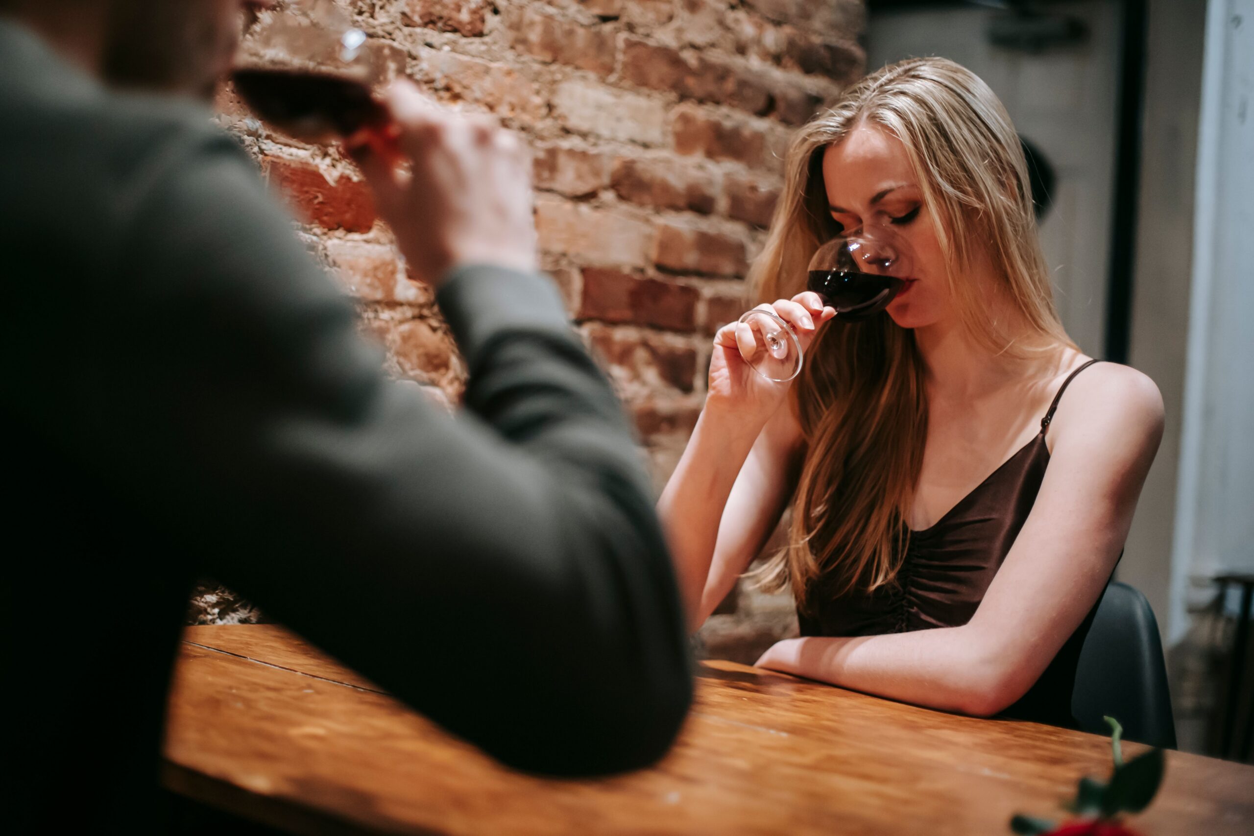 Low angle of young couple enjoying red wine sitting at table in restaurant