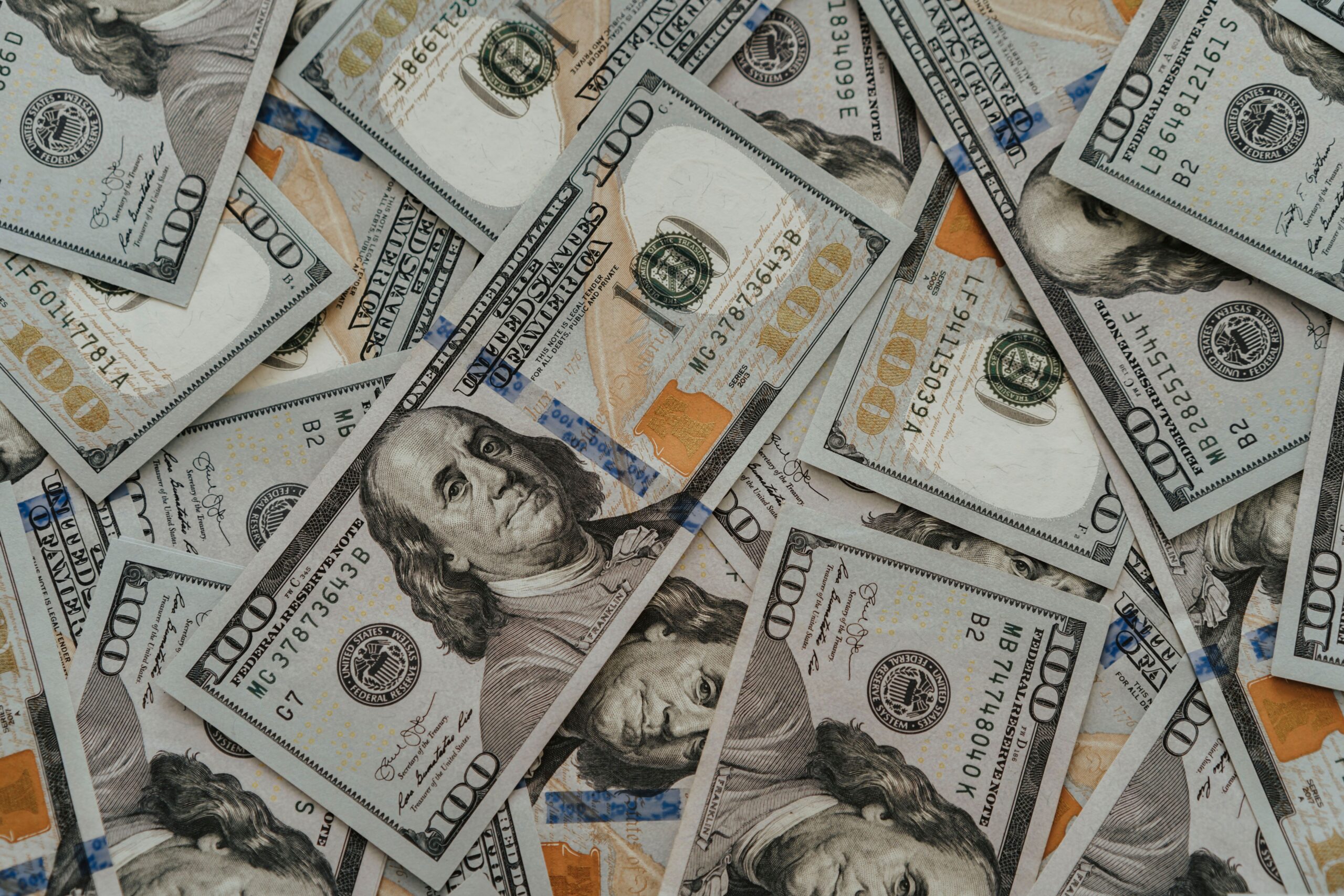 Close-up of American 100 dollar bills scattered, highlighting wealth and currency concepts.