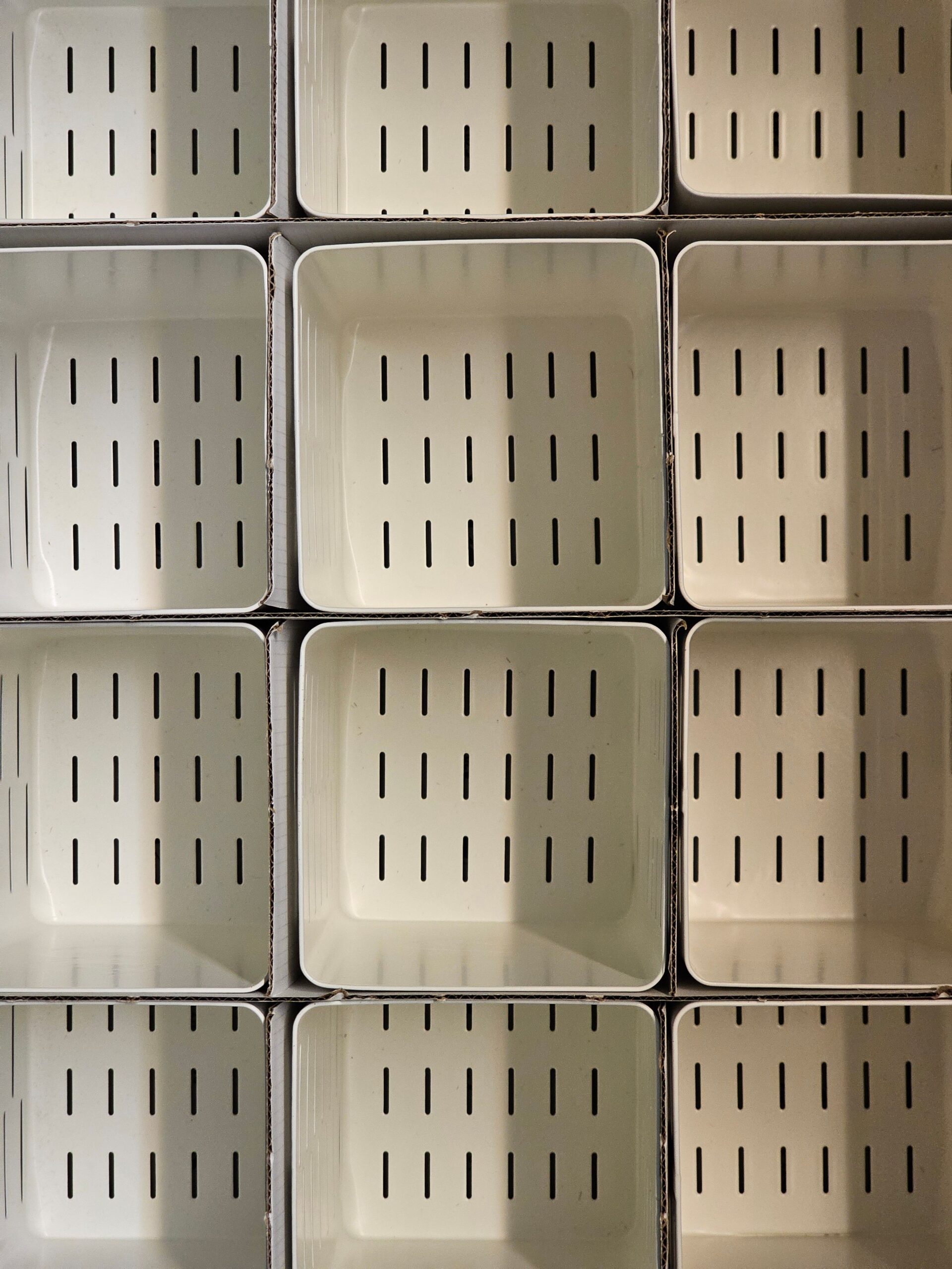 Abstract photo of stacked white containers with slotted design creating a geometric pattern.