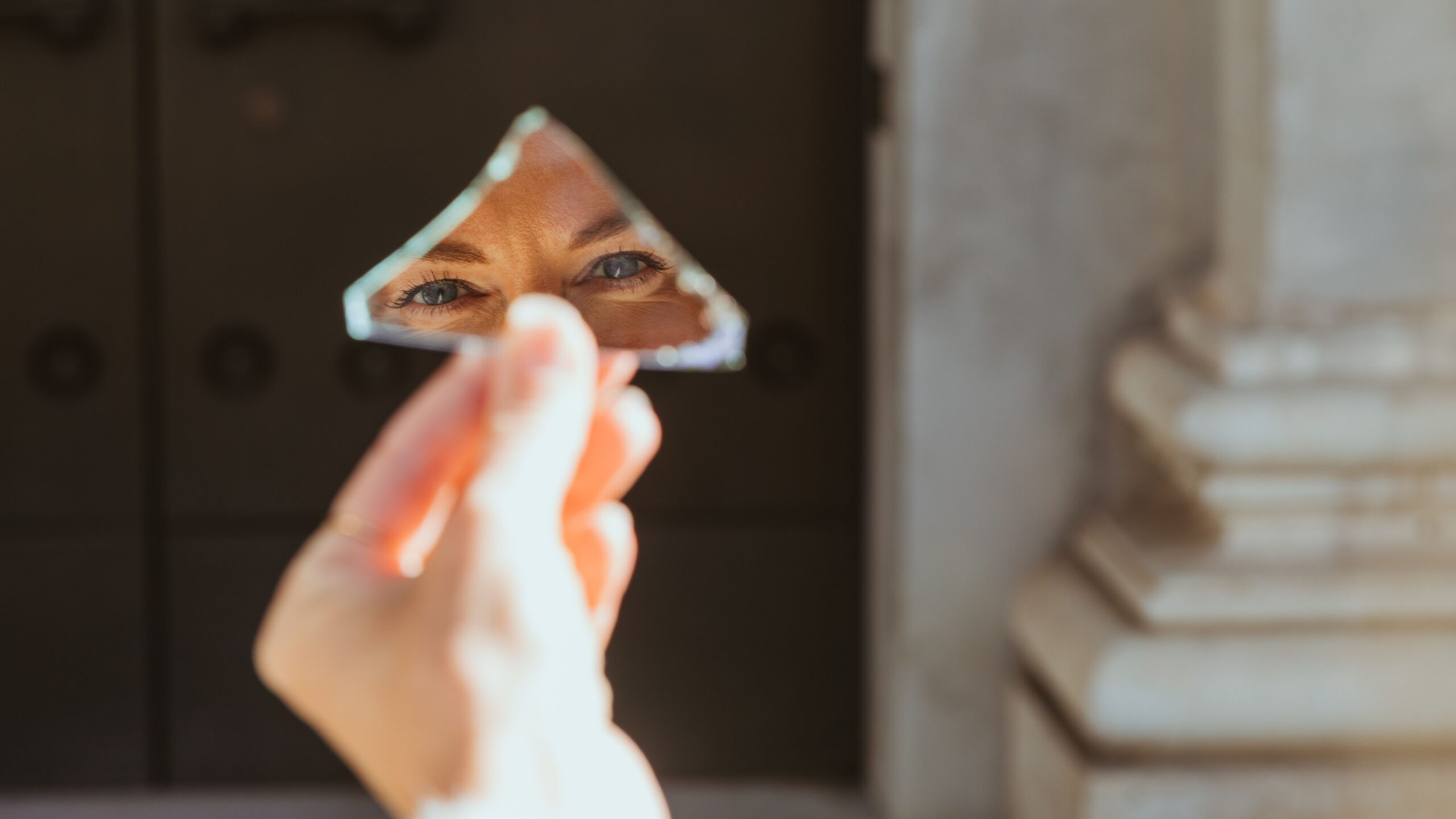 A person's eyes reflecting in a small broken mirror piece held outside in Munich.