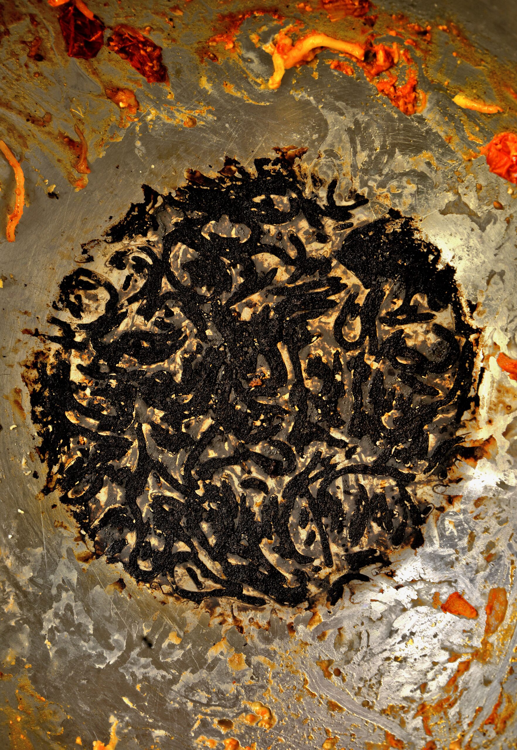 Close-up of burnt food leftovers in a large cooking pan, offering a textured view.