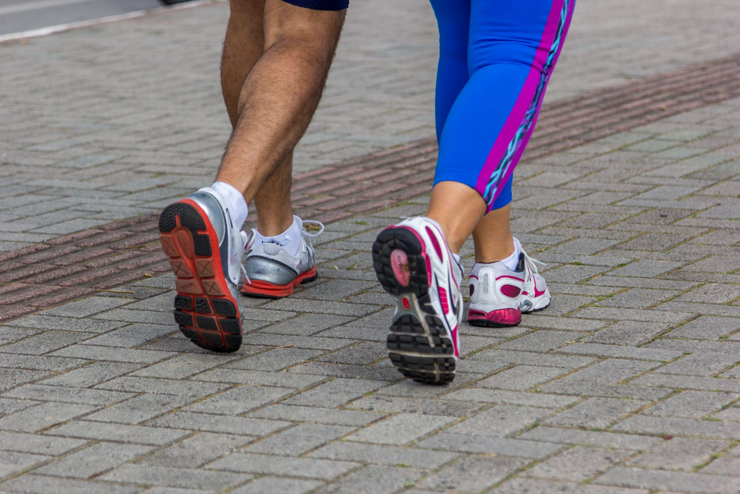 People jogging on a city street, giving a close-up of their sportswear shoes. Urban fitness scene.