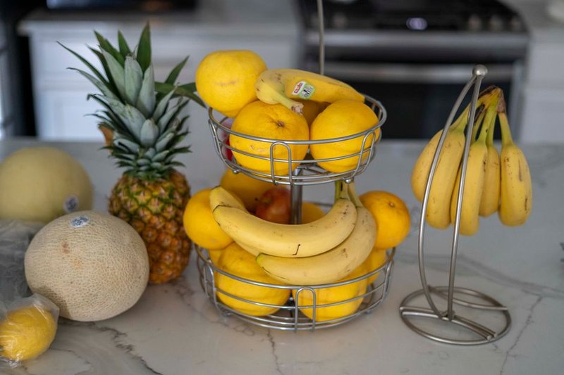 A variety of fresh fruits including pineapples, bananas, and lemons on a modern kitchen counter.